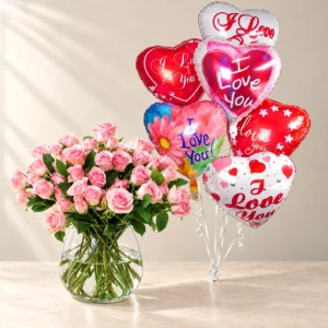 Pink Rosy Cherub spray roses in a clear glass vase beside six printed Love heart balloons